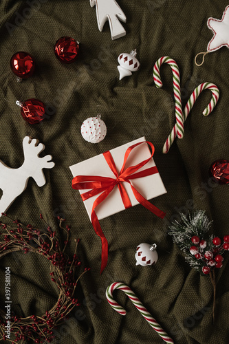 Flatlay of gift box and Christmas toys on crumpled green background. Christmas / New Year holiday celebration decorations. Top view, flat lay. Creative concept for blog, social media. Merry Christmas!