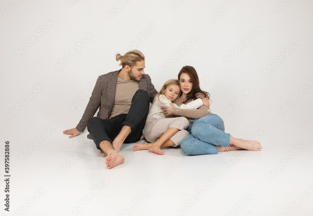 Portrait of attractive father, daughter and mother embracing together in front of grey background. Portrait of attractive father, daughter and mother embracing together in front of grey background.