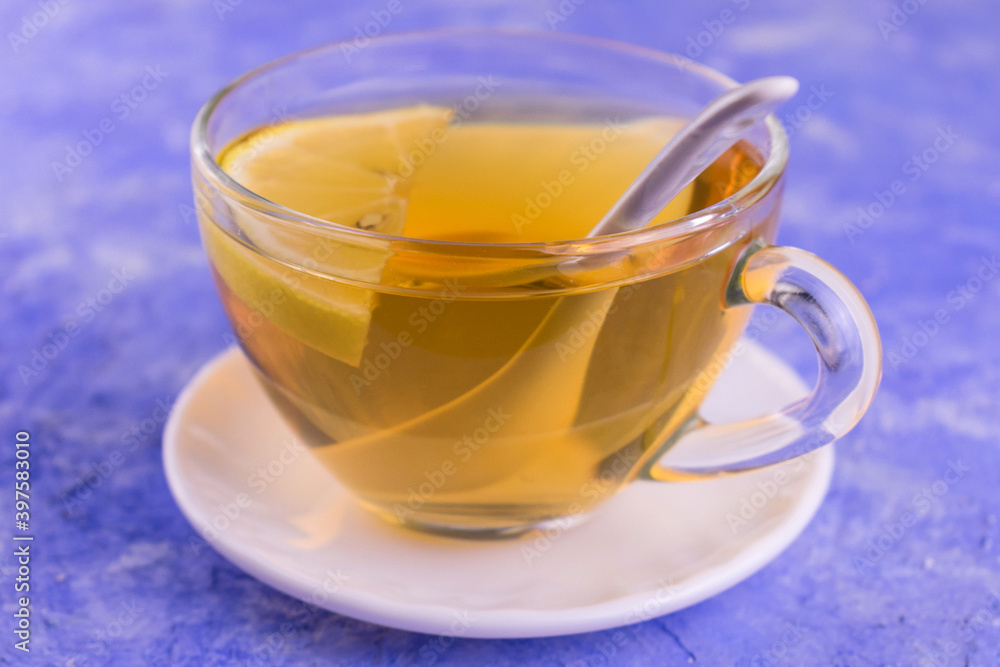 Tea with lemon in a transparent cup on a blue background.
Close-up.
Tea with lemon in a transparent cup on a blue background.
Close-up.