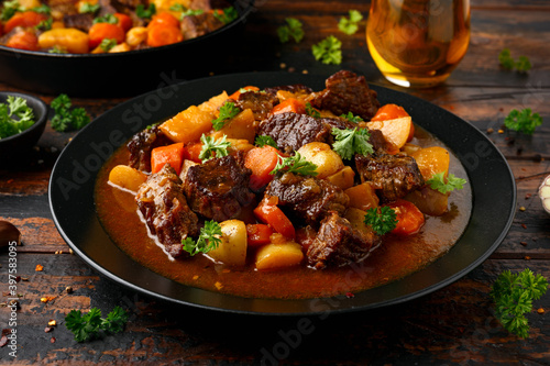 Beef Stew with carrot and baby potato in black plate on wooden table