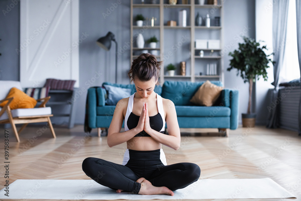 Fototapeta premium Woman sitting in lotus position in living room.