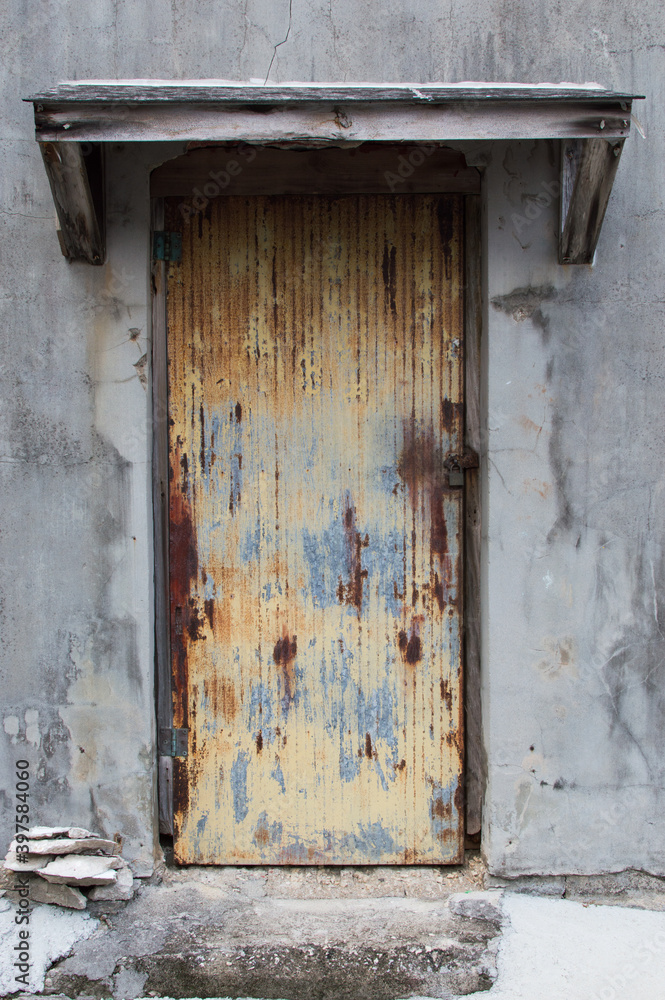 古いコンクリートの建物の赤錆びた鉄板の扉
