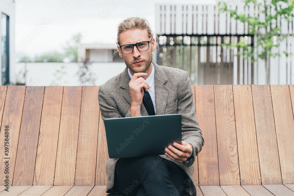 a man in a light business suit with a notebook works on a wooden bench
a man in a light business suit with a notebook works on a wooden bench