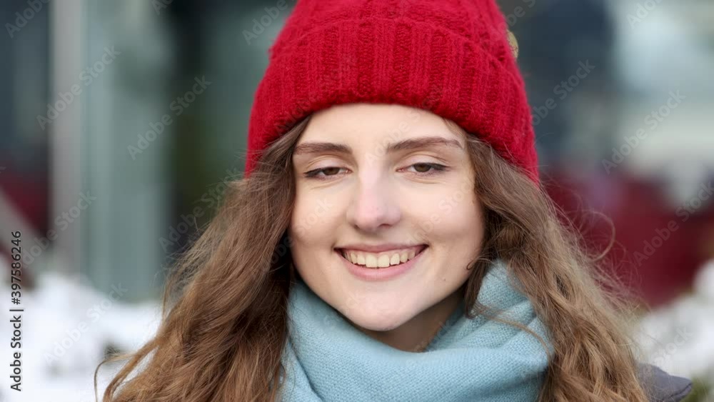 Portrait young attractive curly haired smile woman with red hat look at camera at city center feel happy. Fshion girl. Stand on street. Cute face. CLose up Portrait young attractive curly haired smile woman with red hat look at camera at city center feel happy. Fshion girl. Stand on street. Cute face. CLose up