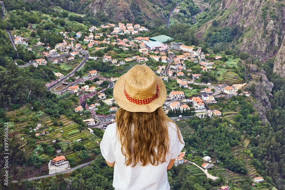 Young girl standing on the edge of the cliff watching the view. Holiday mountain village landscape. Travel lifestyle background. Curral das freiras on Madeira island.