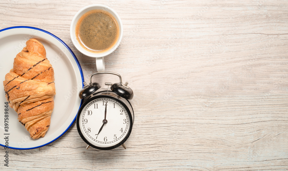 morning quick breakfast with croissant and coffee with an alarm clock on the background with space for text morning quick breakfast with croissant and coffee with an alarm clock on the background with space for text