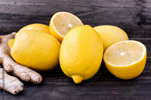 Lemons, ginger root on a rustic, wooden background. Cut and whole citrus fruits.