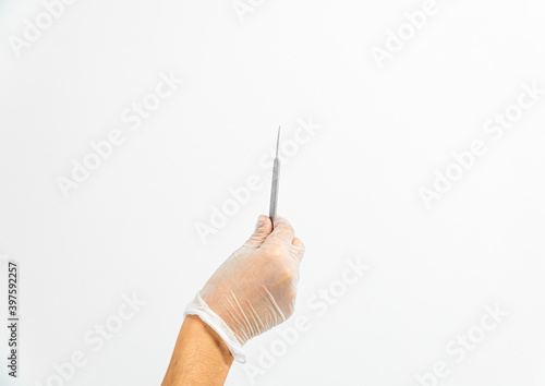 Close-up of a podiatrist's hand with gloves holding gouge on a white background