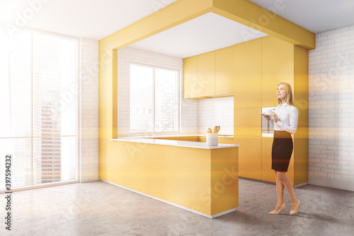 Woman in yellow kitchen with cupboards