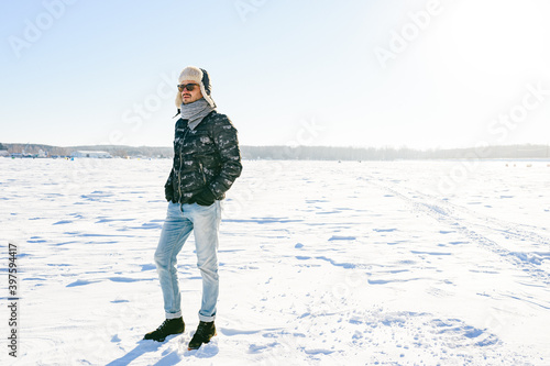 Dreaming stylish man in sunglasses posing in the snow field