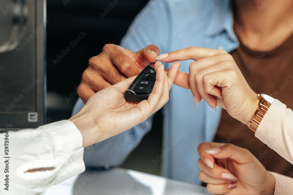 Car salesperson giving keys to a client close up