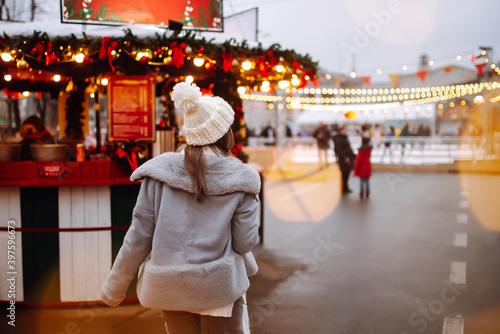 Happy woman  drinking hot coffee in Festive Christmas fair. Beautiful woman enjoys winter holidays on Christmas market. New year.Lights around. © maxbelchenko