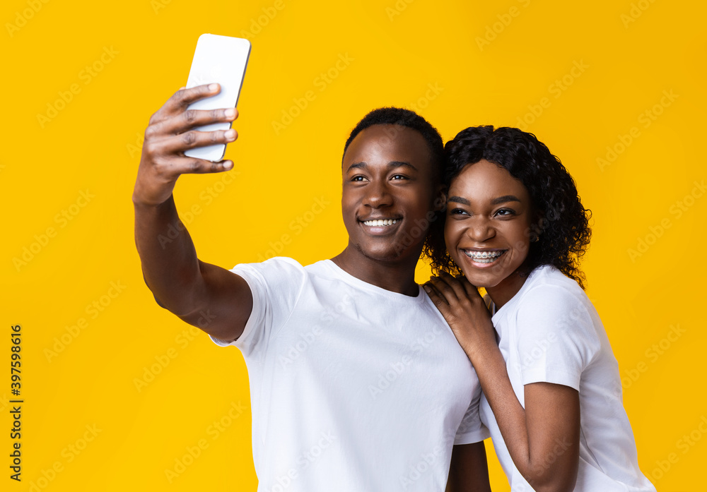 Cheerful african american couple taking selfie on mobile phone Cheerful african american couple taking selfie on mobile phone