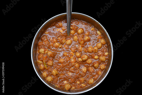 picture of chole chana masala sabji in round vessel with spoon and black background photo