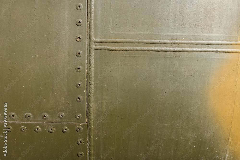 Details of the fuselage of an old aircraft. Old camouflage surface with exfoliated paint and rivets on a military aircraft. Details of the fuselage of an old aircraft. Old camouflage surface with exfoliated paint and rivets on a military aircraft.