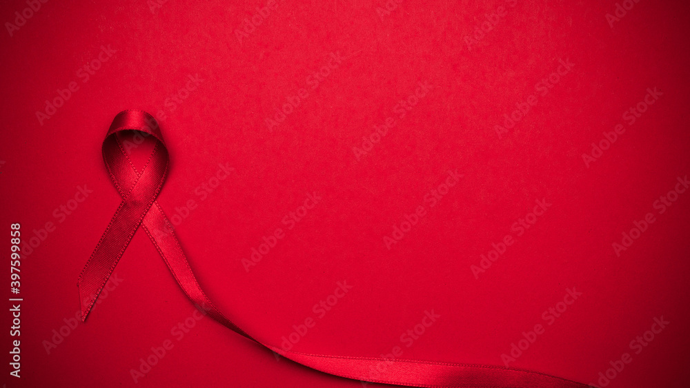 Aids day. Red ribbon symbol in hiv world day on dark red background. Awareness aids and cancer. Healthcare and medical concept. - obrazy, fototapety, plakaty 