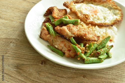 spicy stir fried fermenting soft pork and slice yard long bean curryeat couple plain rice topping crispy egg on plate
