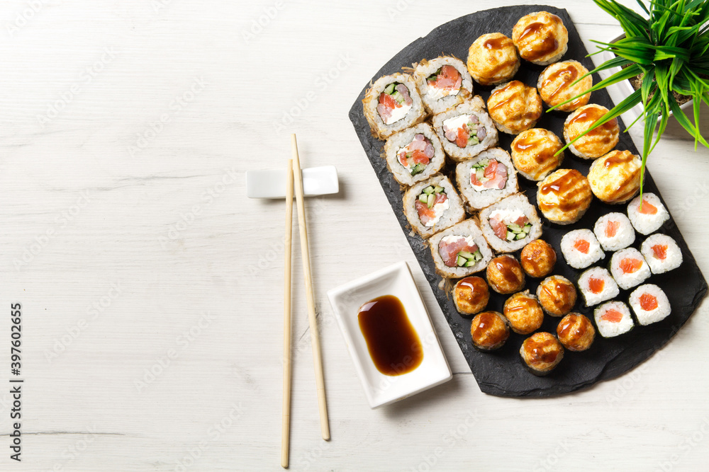 Sushi rolls set on a stone Board for sushi on a light backgroundSushi rolls set on a stone Board for sushi on a light background