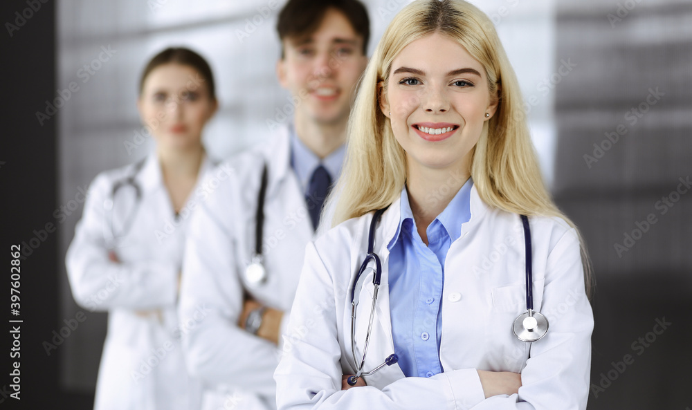 Group of three young doctors standing as a team with arms crossed in modern clinic and ready to help patients. Medicine concept Group of three young doctors standing as a team with arms crossed in modern clinic and ready to help patients. Medicine concept