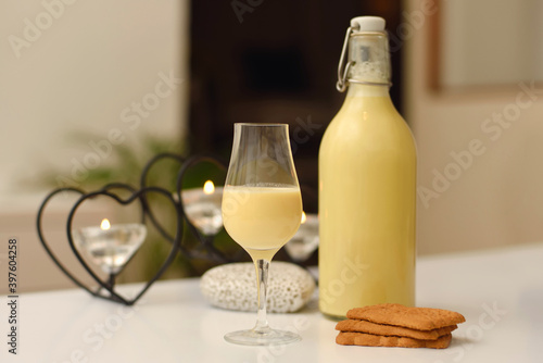 Homemade eggnog in bottle and one glass on white background