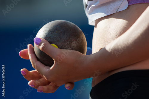 The athlete holds the projectile (shot) in the shot put. Close-up