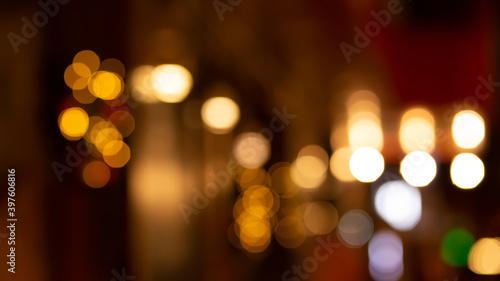 Abstract evening night shimmering bokeh background effect outside near cafe restaurant. Defocused urban city life blur golden light bulbs wreath garlands. Christmas New Year party holiday concept

