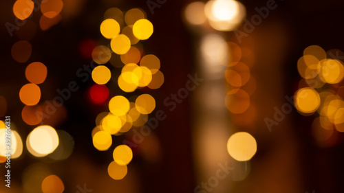 Abstract evening night shimmering bokeh background effect outside near cafe restaurant. Defocused urban city life blur golden light bulbs wreath garlands. Christmas New Year party holiday concept 
