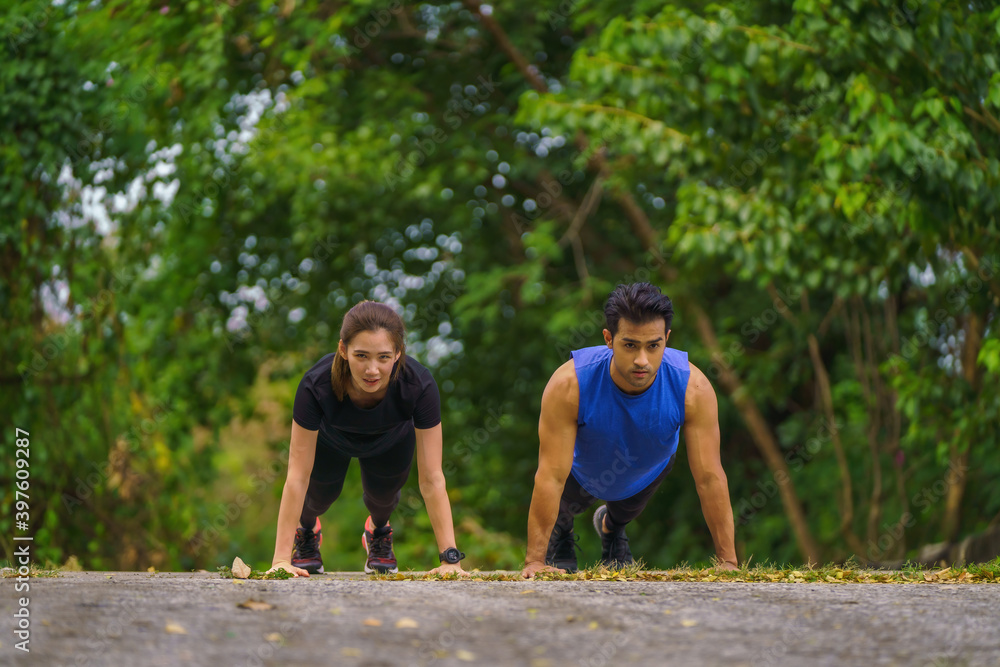 Obraz premium asian athletic couple having push up exercise together outdoors in park