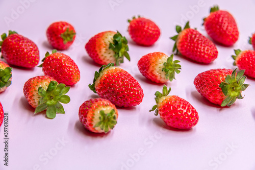 Abstract strawberry background. Ripe red strawberry fruits lies in diagonal lines on purple background. Selective focus. Summer food theme.