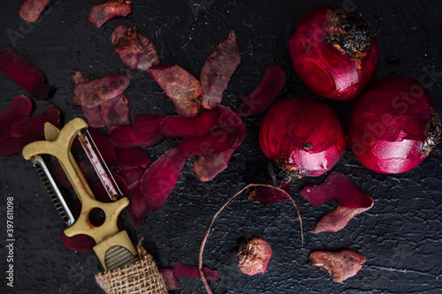 Moody and artistic top view of peeled beetroots on a black background with skins and a knife. Fresh, farm, market, organic, produce, agriculture concept.