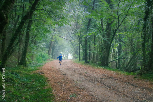 enfant en train de courir dans une forêt pendant une averse de pluie en été