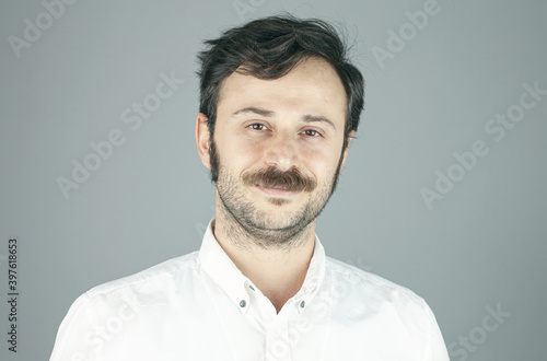 Handsome young man on grey background looking at camera.