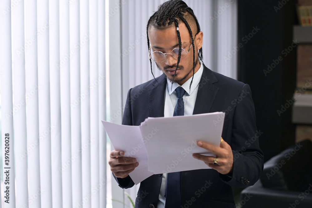 A young stylish black unusual office employee examines the received documents, carefully examines them. Young boss with an unusual appearance in the office A young stylish black unusual office employee examines the received documents, carefully examines them. Young boss with an unusual appearance in the office