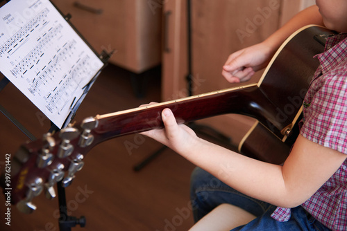 a little girl learns to play the guitar from notes. Music school for children.Musical notation.