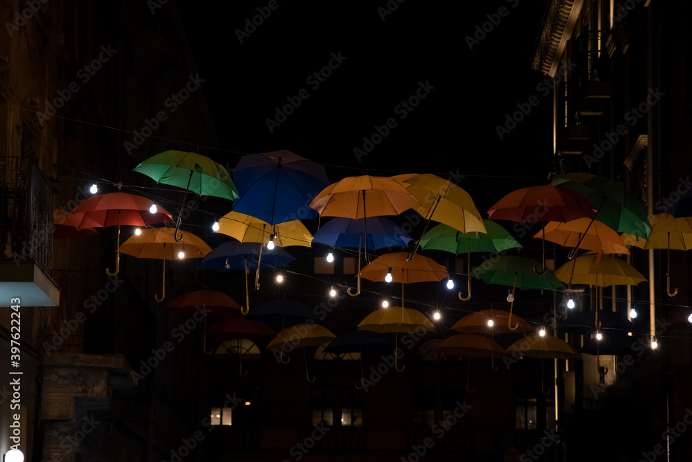 evening street landmark view with decoration objects colorful hanging umbrellas with garland lights soft focus picture