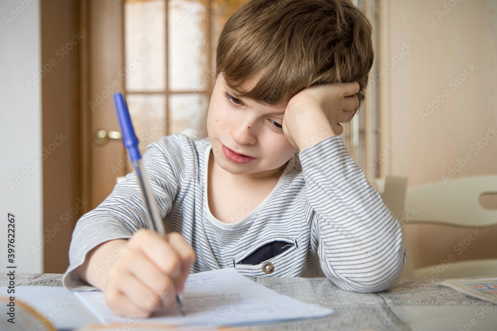 A first-grader boy does his homework in isolation. A first-grader boy does his homework in isolation.