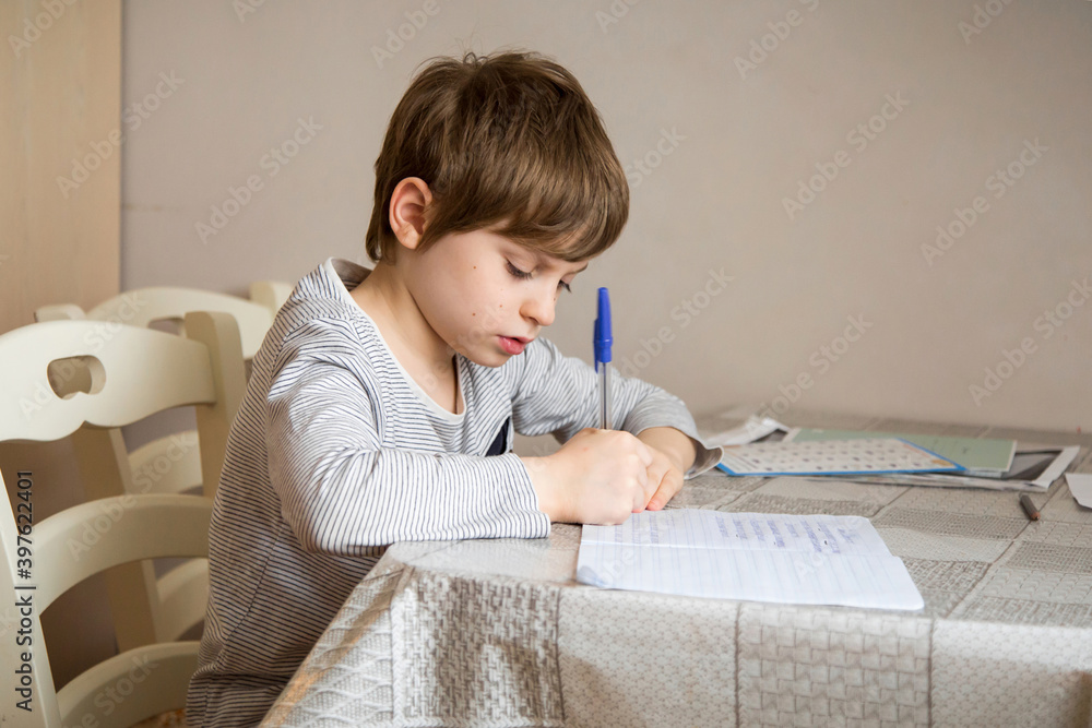 A first-grader boy does his homework in isolation. A first-grader boy does his homework in isolation.