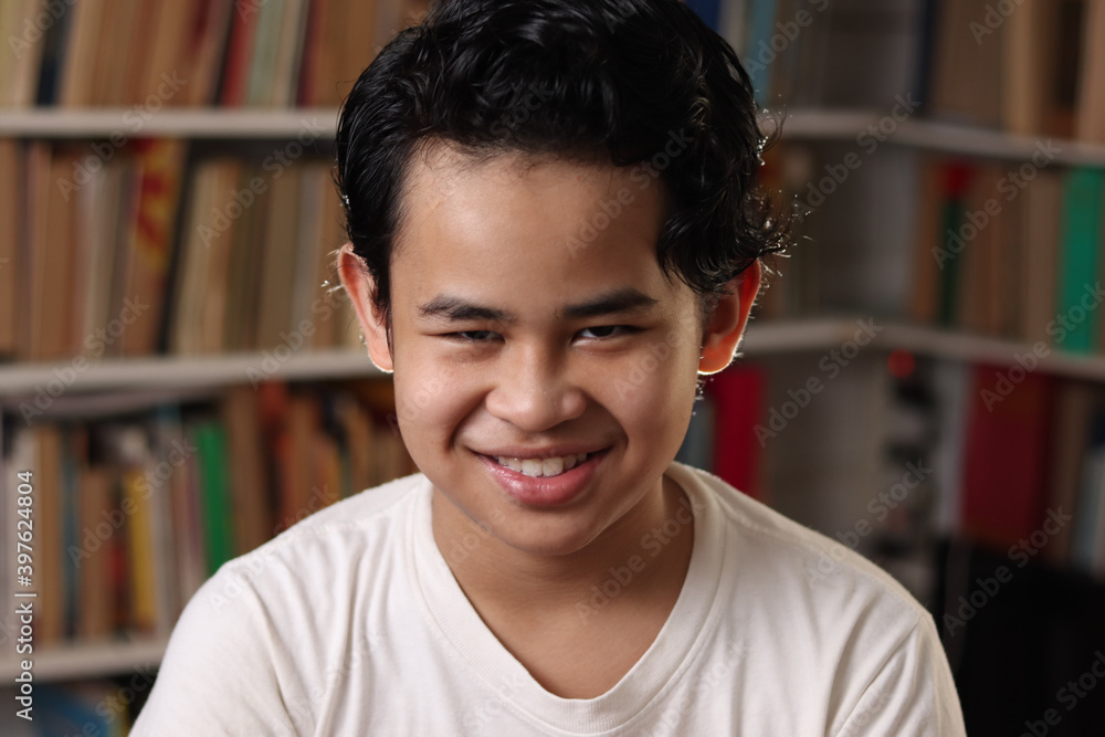 Happy cheerful Asian student boy smiling to camera, kid learning in library Happy cheerful Asian student boy smiling to camera, kid learning in library