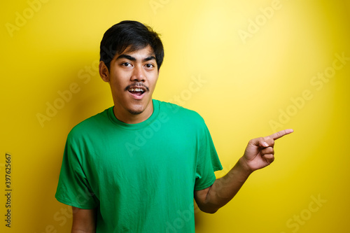 Smiling handsome Asian man pointing finger to empty open hand