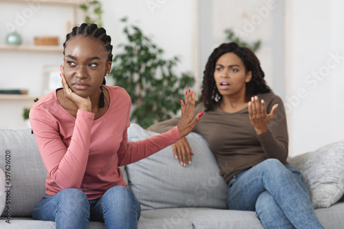 Annoyed black woman showing stop gesture to her scolding girlfriend photo