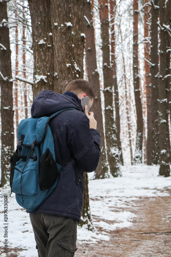 A man walks on a forest path in winter and talks on the phone. It snowed.