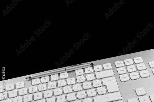 PC keyboard and pen against black background photo