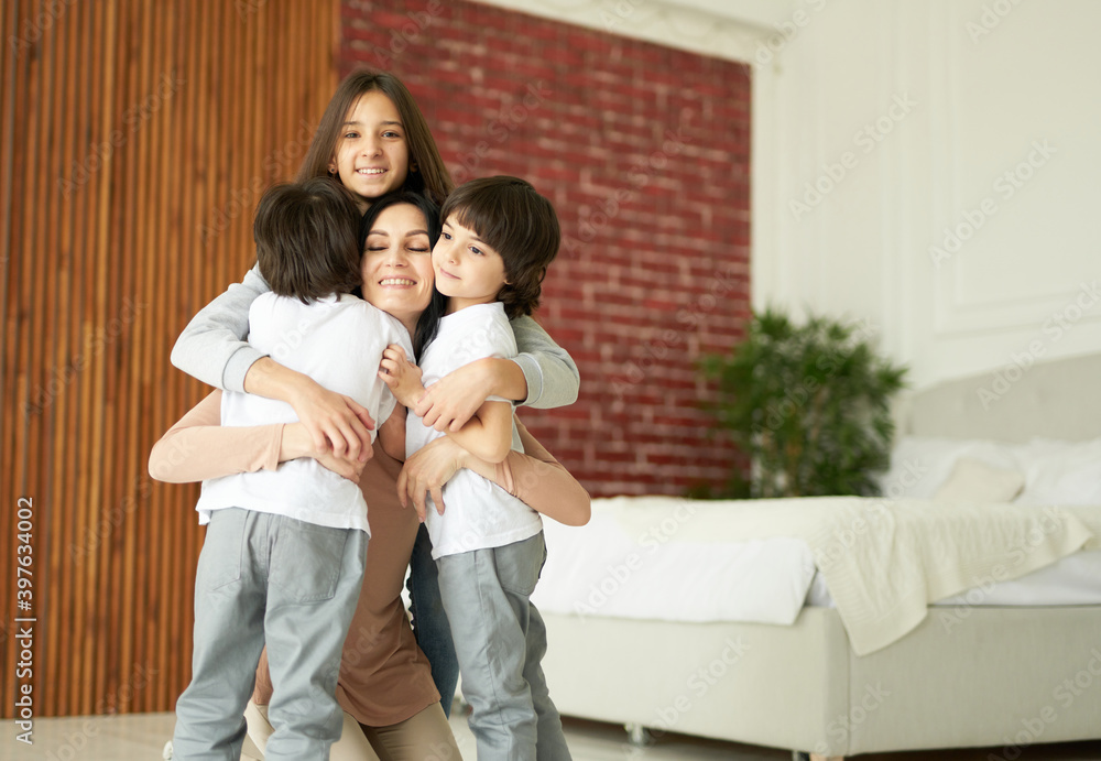 Love your kids. Happy latin children, teenage girl and two little twin boys hugging their mother while having fun together indoors. Mom playing with her children at home Love your kids. Happy latin children, teenage girl and two little twin boys hugging their mother while having fun together indoors. Mom playing with her children at home