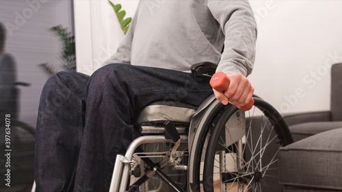 Man in wheelchair exercising and lifting weight in a living room.