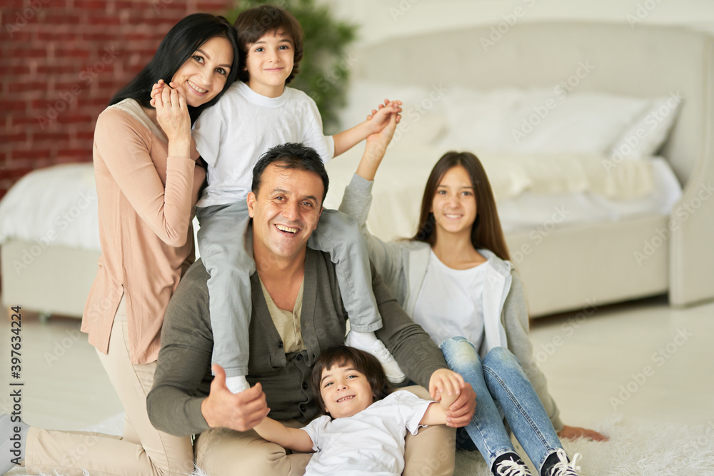 Radiating happiness. Portrait of latin family, teenage daughter and little boys smiling at camera while posing with their parents at home Radiating happiness. Portrait of latin family, teenage daughter and little boys smiling at camera while posing with their parents at home