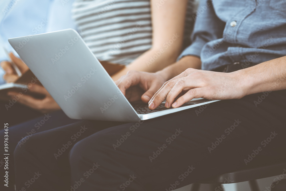 Group of casual dressed business people working at meeting or conference, close-up of hands. Businessman using laptop computer. Teamwork or coaching concept Group of casual dressed business people working at meeting or conference, close-up of hands. Businessman using laptop computer. Teamwork or coaching concept