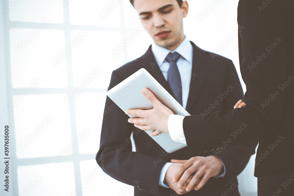 Businessman and woman using tablet computer for discussing questions in office. Partners or colleagues at meeting. Business cooperation concept Businessman and woman using tablet computer for discussing questions in office. Partners or colleagues at meeting. Business cooperation concept
