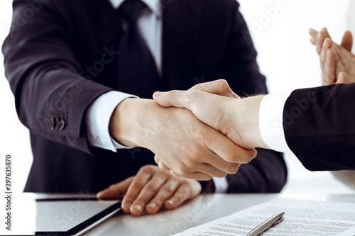 Business people shaking hands after contract signing in modern office. Teamwork and handshake concept