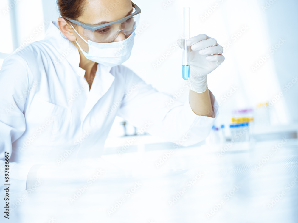 Female laboratory assistant analyzing test tube with blue liquid. Medicine, health care and researching concept Female laboratory assistant analyzing test tube with blue liquid. Medicine, health care and researching concept