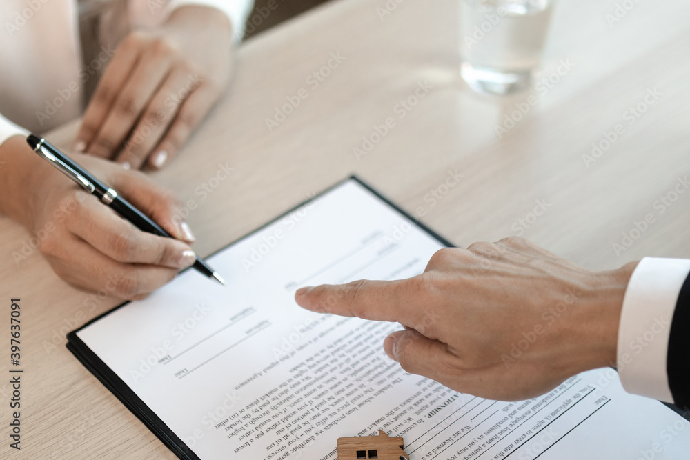 The apartment landlord is pointing to the contract to keep tenants sign on paperwork. The apartment landlord is pointing to the contract to keep tenants sign on paperwork.